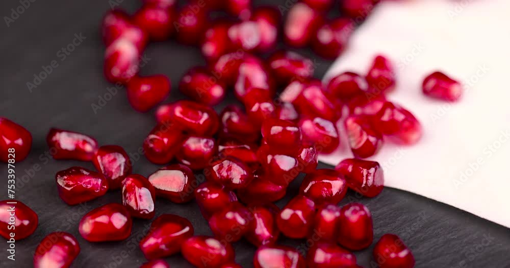 red grains of peeled pomegranate fruit, large sweet and juicy pomegranate seeds on a table made of black slate red grains of peeled pomegranate fruit, large sweet and juicy pomegranate seeds on a table made of black slate