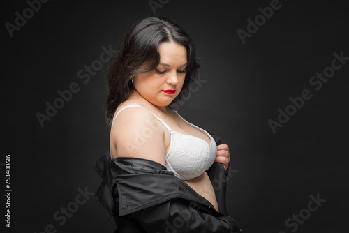 A woman in a black jacket wears a white bra. The concept of confidence and empowerment as a woman proudly shows off her bra. A black jacket adds sophistication. Fat woman.