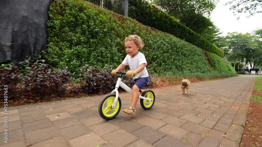 Playful duo of young child and puppy run on sidewalk, with energetic toddler racing on balance bike and little puppy jogging behind. Their vibrant camaraderie and shared joy create delightful scene Playful duo of young child and puppy run on sidewalk, with energetic toddler racing on balance bike and little puppy jogging behind. Their vibrant camaraderie and shared joy create delightful scene
