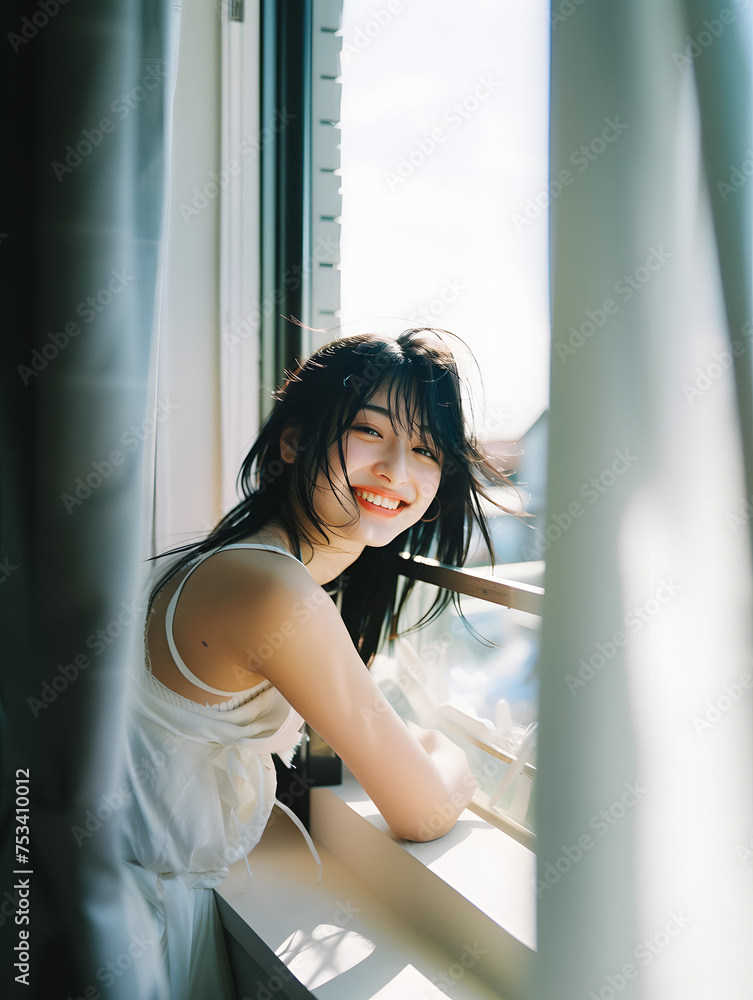 窓辺の自然光を浴びる笑顔のアジア人女性