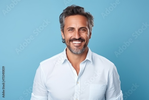 Portrait of handsome mature man smiling at camera over blue background. © Loli
