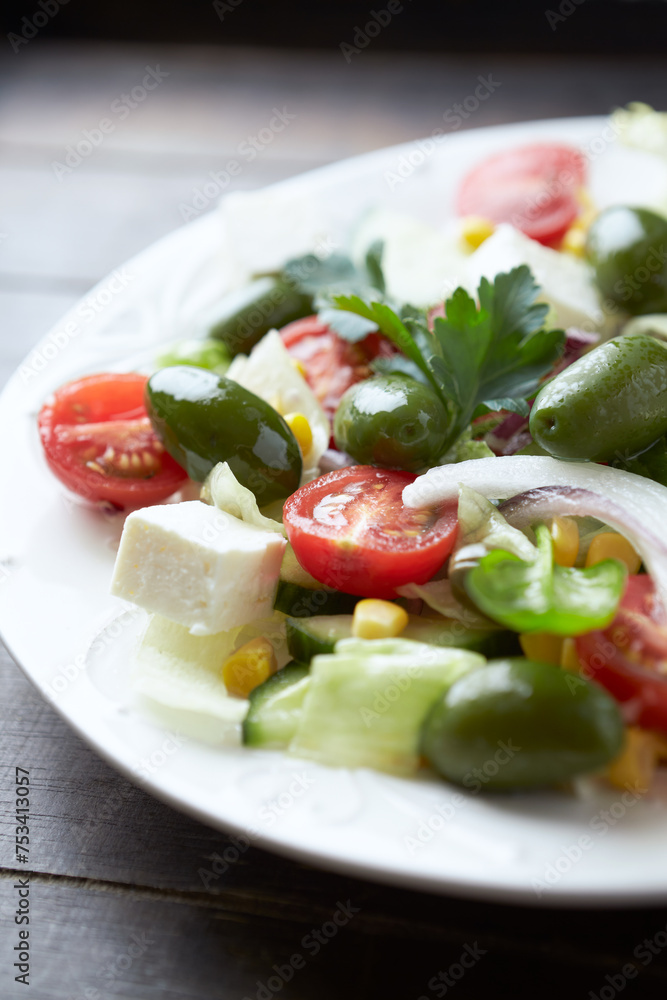 Salad with Feta Cheese, Green Olives, Baby Spinach, Cucumber, Cherry Tomatoes and Capers. Dark wooden background. Close up. Salad with Feta Cheese, Green Olives, Baby Spinach, Cucumber, Cherry Tomatoes and Capers. Dark wooden background. Close up.