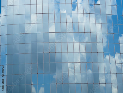 Blue sky with clouds reflected in glass windows of skyscraper