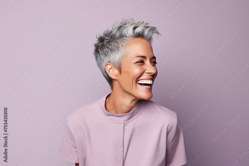 Cheerful mature woman with short grey hair. Portrait of beautiful mature woman laughing while standing against purple background Cheerful mature woman with short grey hair. Portrait of beautiful mature woman laughing while standing against purple background