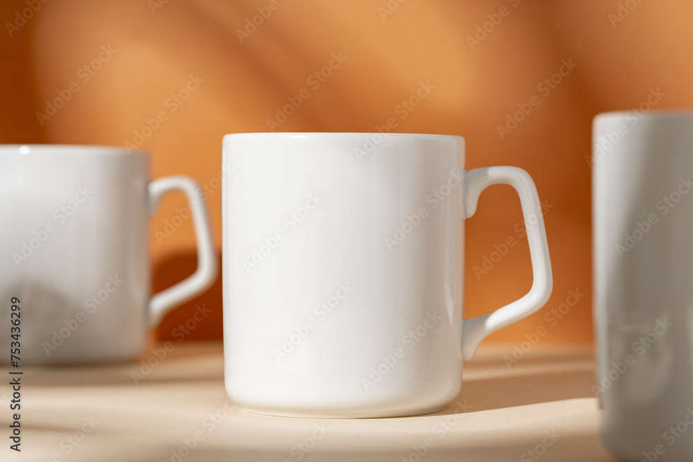 White ceramic mugs on peach background with shadows White ceramic mugs on peach background with shadows