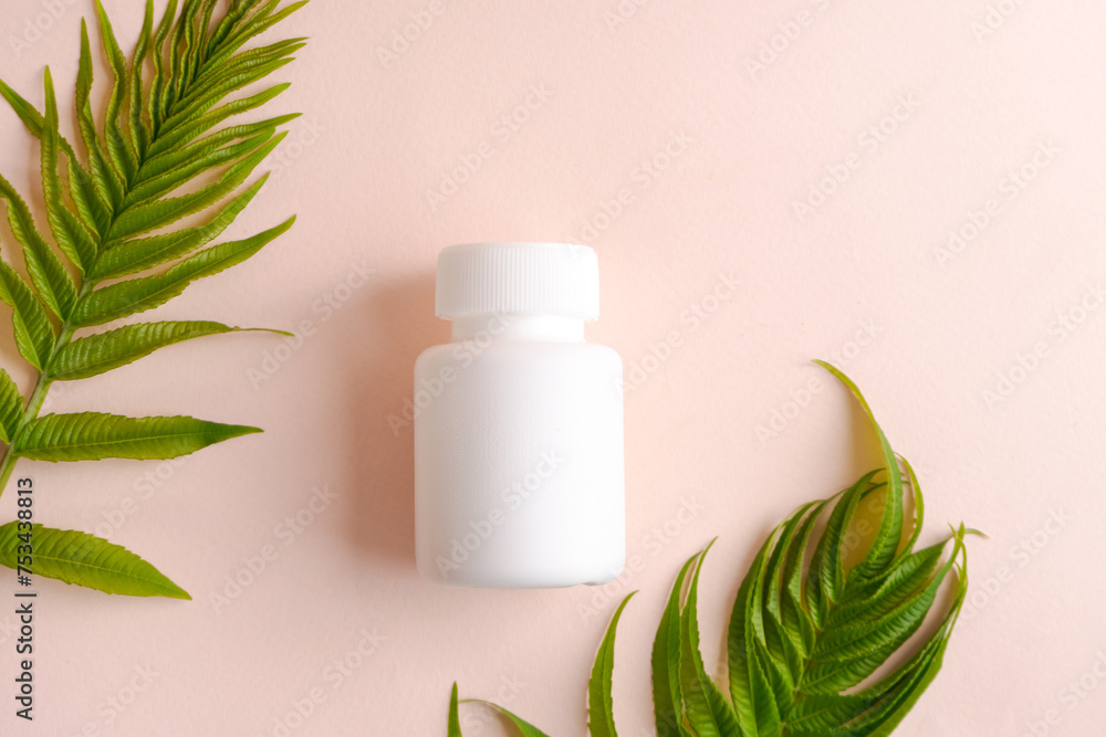 A white pill bottle is on pink background with green leaves