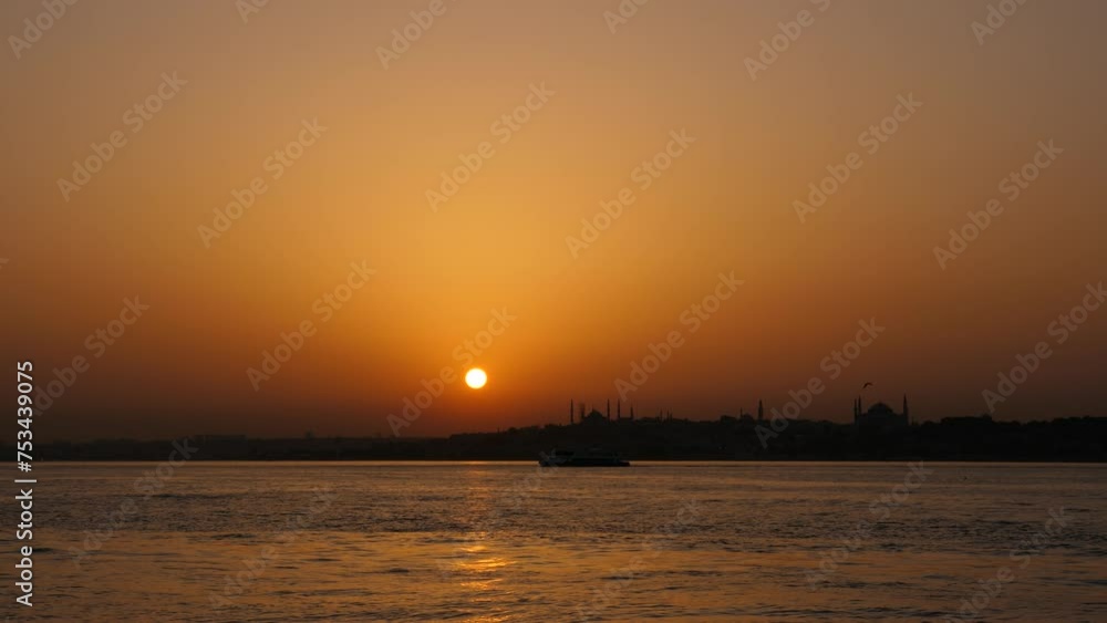 Beautifully abstract view of evening Istanbul. Calm waters of Marmara Sea and Bosporus, with silhouette of Fatih on opposite shore. Darkened city skyline featuring distinctive shapes of Hagia Sophia Beautifully abstract view of evening Istanbul. Calm waters of Marmara Sea and Bosporus, with silhouette of Fatih on opposite shore. Darkened city skyline featuring distinctive shapes of Hagia Sophia