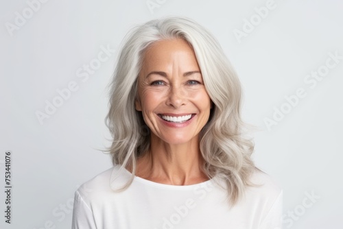 Portrait of a beautiful senior woman smiling at the camera on grey background