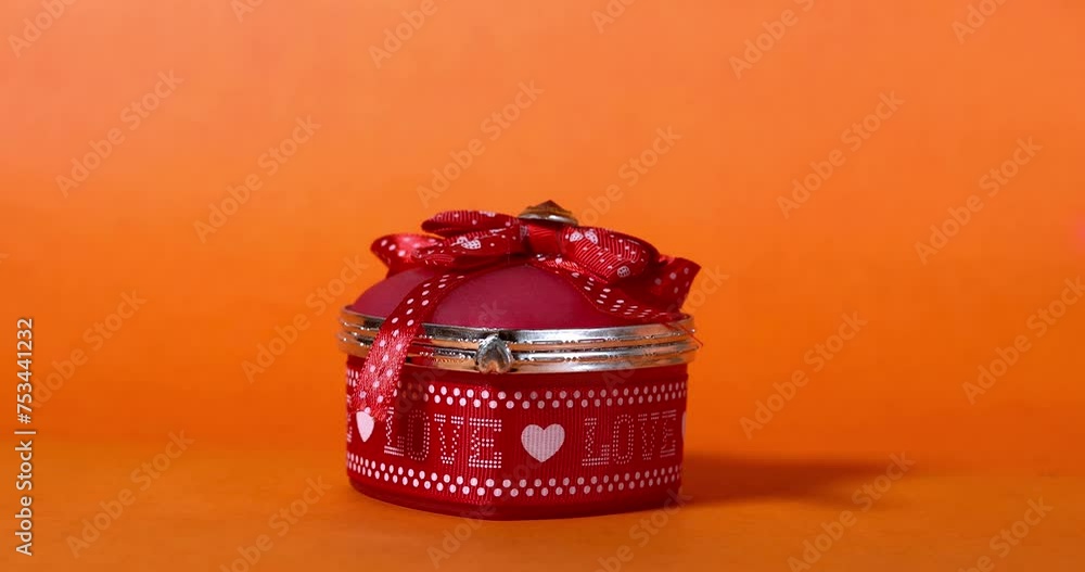 Indian woman hand placing beautiful red heart shaped jewelry box expressing love on orange background. Gift for Valentine's Day, Mother's Day, Father's Day, Friendship Day. Indian woman hand placing beautiful red heart shaped jewelry box expressing love on orange background. Gift for Valentine's Day, Mother's Day, Father's Day, Friendship Day.