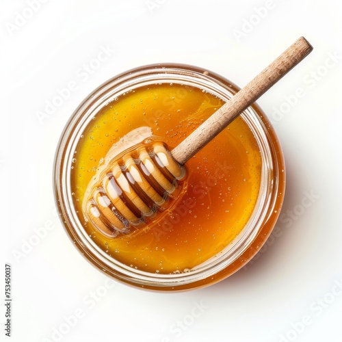 Top view of a glass jar of honey with dipper isolated on white background