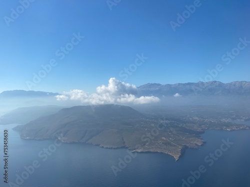 top view of an island in the sea with clouds and mountains on a sunny day