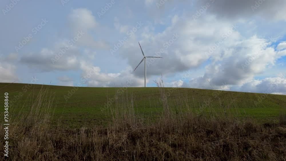 Wind turbine on a grassy hill with a cloudy sky backdrop. Wind turbine on a grassy hill with a cloudy sky backdrop.
