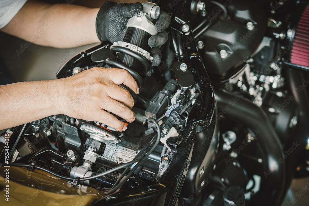 motorcycle mechanic replace rear Shock Absorbers on motorcycle at garage, repair, maintenance and service concept