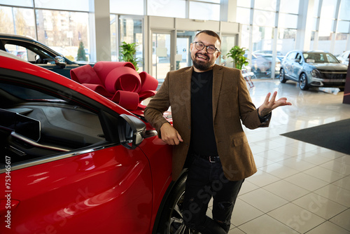 Caucasian guy stands next to a red car