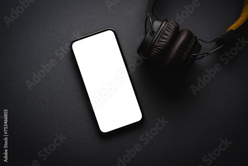 Retro style wireless over-ear headphones and smartphone with blank screen on dark gray background photo