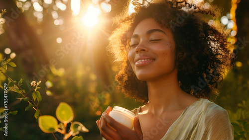 The model is closing her eyes and smiling peacefully while holding a skincare jar in the golden hour photo