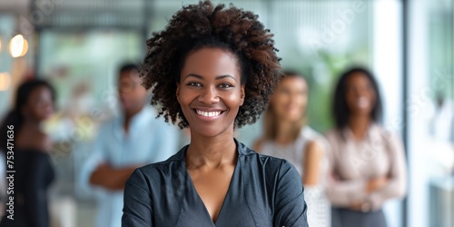 Charismatic businesswoman with team. Portrait of a smiling African American woman with colleagues in the background at office, team leader