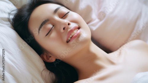 A beautiful asian female is enjoying and feels good. Woman's face during an orgasm in bed. Women's pleasure.