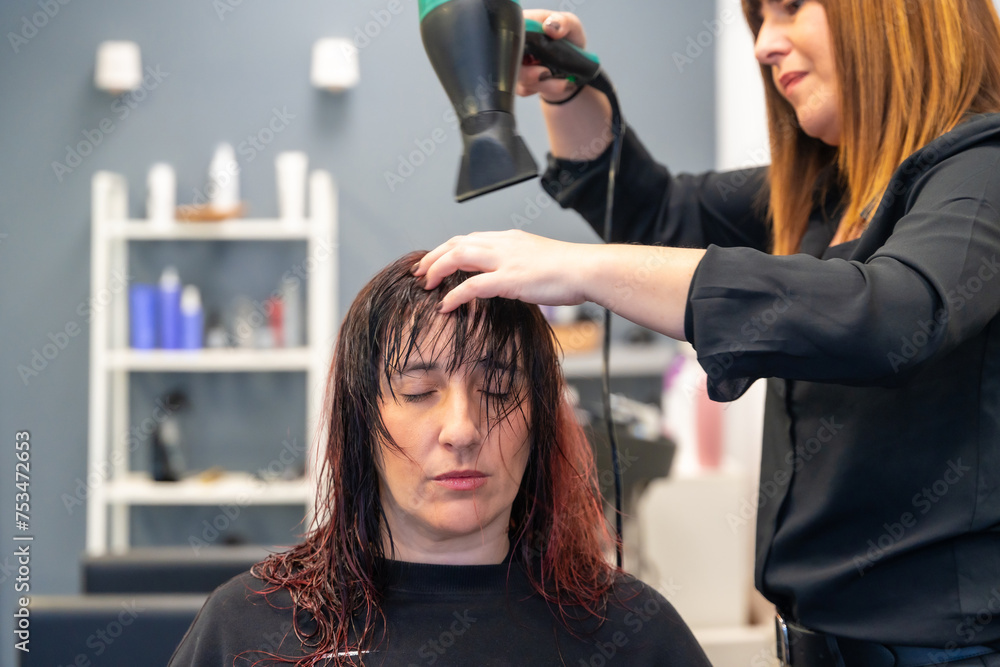 Fototapeta premium Hairdresser drying the hair of a patient woman