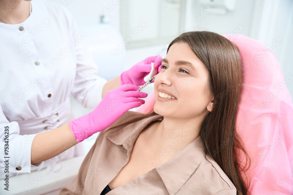 Cosmetician with syringe make face injection to young female Cosmetician with syringe make face injection to young female