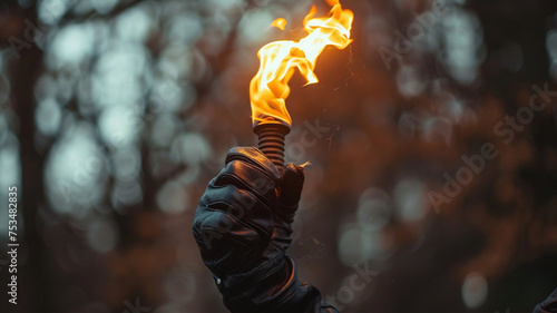 a hand with a black leather glove holding a olympic fire torch 