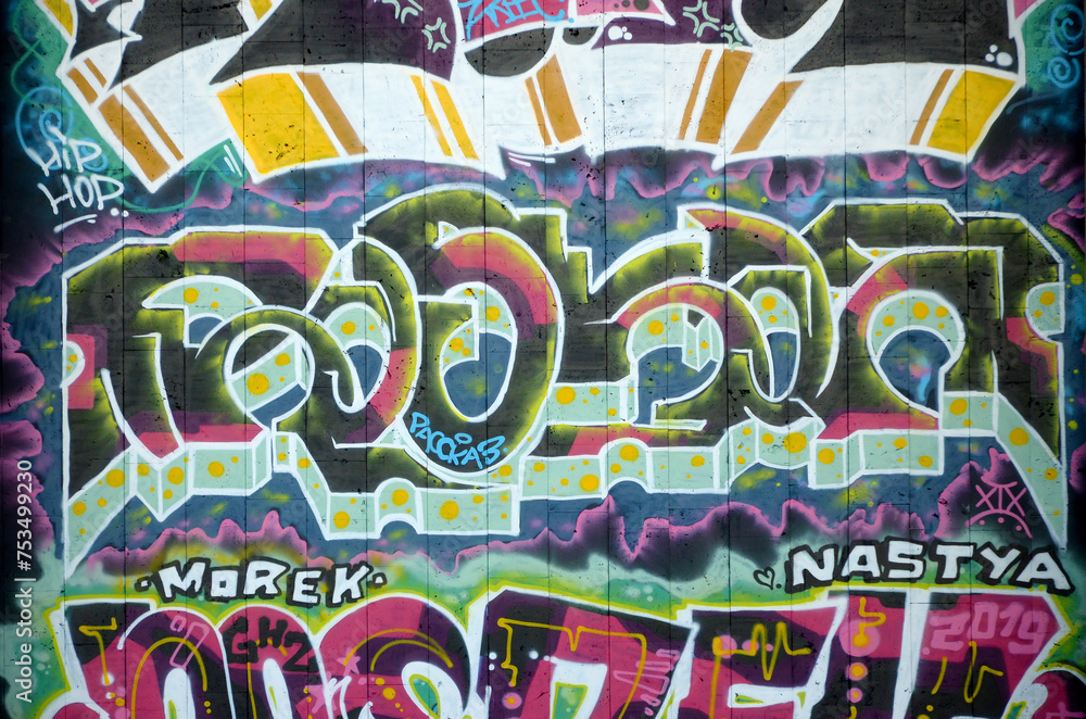 The old wall decorated with paint stains in the style of street art culture. Colorful background of full graffiti painting artwork with bright aerosol outlines on wall. Colored background texture The old wall decorated with paint stains in the style of street art culture. Colorful background of full graffiti painting artwork with bright aerosol outlines on wall. Colored background texture