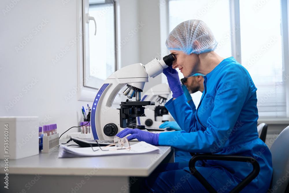 Female virologist examines biological material under a microscope Female virologist examines biological material under a microscope