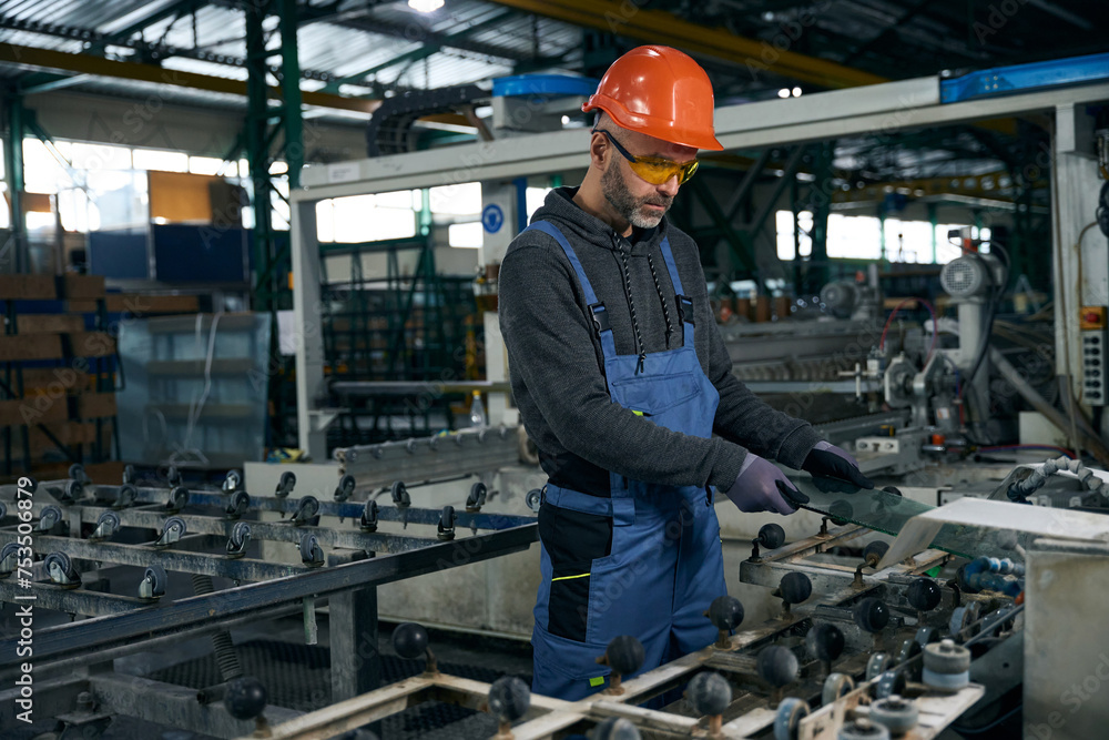 Middle-aged man processes the edge of glass using high-tech equipment Middle-aged man processes the edge of glass using high-tech equipment