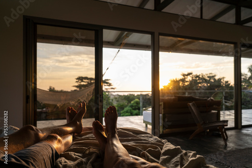 Ein Paar blickt aus dem Bett am Morgen in den Sonnenaufgang 
