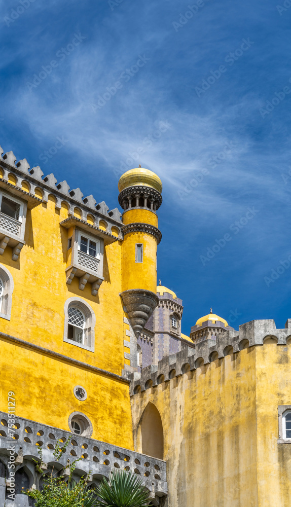 Exterior view of the watchtower of the colorful yellow Pena Palace under a sunny blue sky. Sintra. Portugal. Copy space. Vertical banner.
