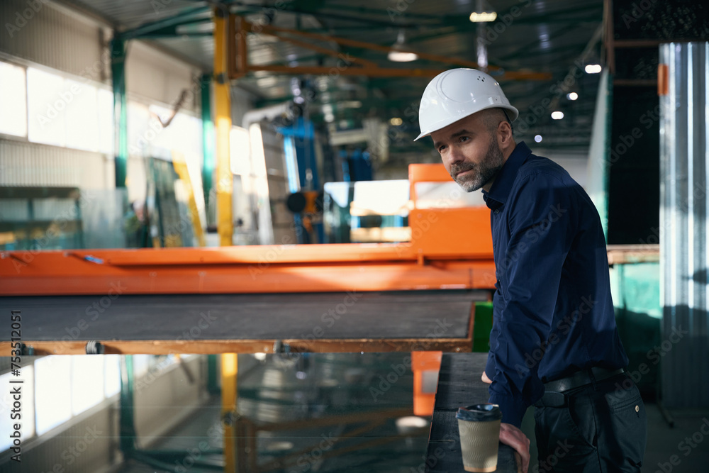 Man in safety helmet at workplace in window production facility Man in safety helmet at workplace in window production facility