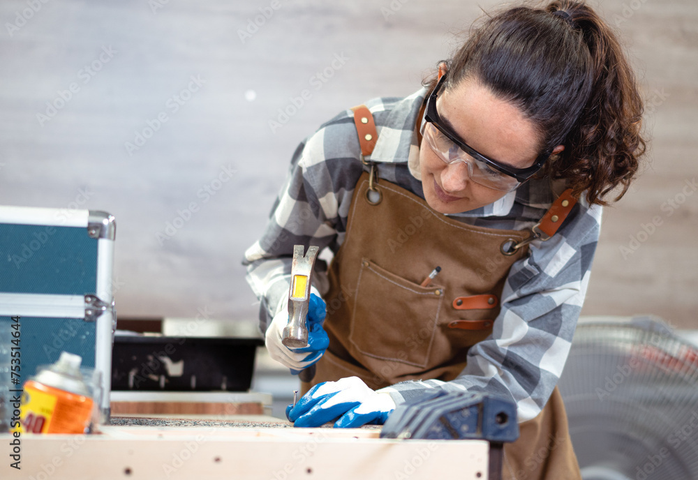 Female latino carpenter using tool busy working her job in furniture renovation small business. Hispanic woman wear goggles standing in DIY carpentry workshop. Empowerment joiner women in woodworking. Female latino carpenter using tool busy working her job in furniture renovation small business. Hispanic woman wear goggles standing in DIY carpentry workshop. Empowerment joiner women in woodworking.