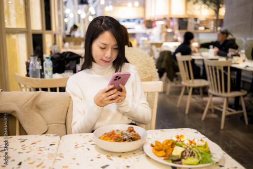 Woman use mobile phone to take photo on her food in restaurant