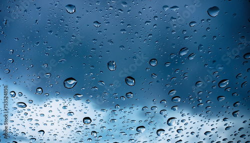 Water drops on a glass pane in front of dark rain clouds in blue colors; artistic photo for your design