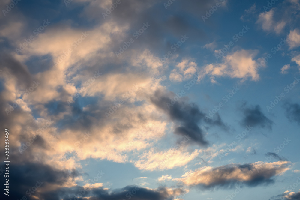 Cloudy sky in golden sun rays in sunset or sunrise, natural background