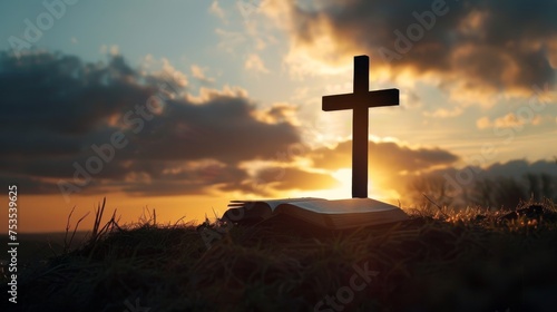 Silhouetted cross on a hill with sunrise and open Bible