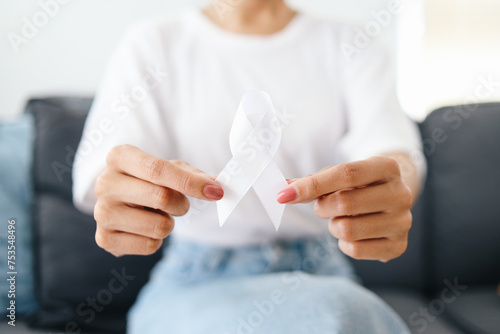 Woman in white t- shirt holding white ribbon for supporting mental health awareness campaign and lung cancer awareness