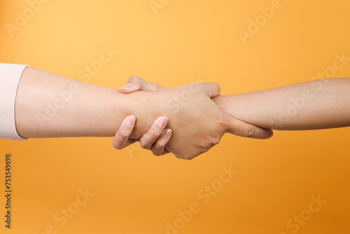 Foto Two hands grabbing each other wrist to helping over yellow background