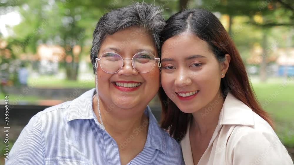 An elderly mother hugs her daughter, both smiling happily in the garden outside. Family concept. Health insurance An elderly mother hugs her daughter, both smiling happily in the garden outside. Family concept. Health insurance