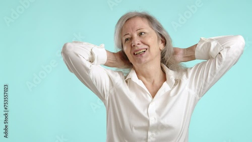 A serene mature woman enjoys a satisfying morning stretch, arms raised behind her head, in a relaxed white shirt, conveying a feeling of refreshment and comfort. Camera 8K RAW.  photo