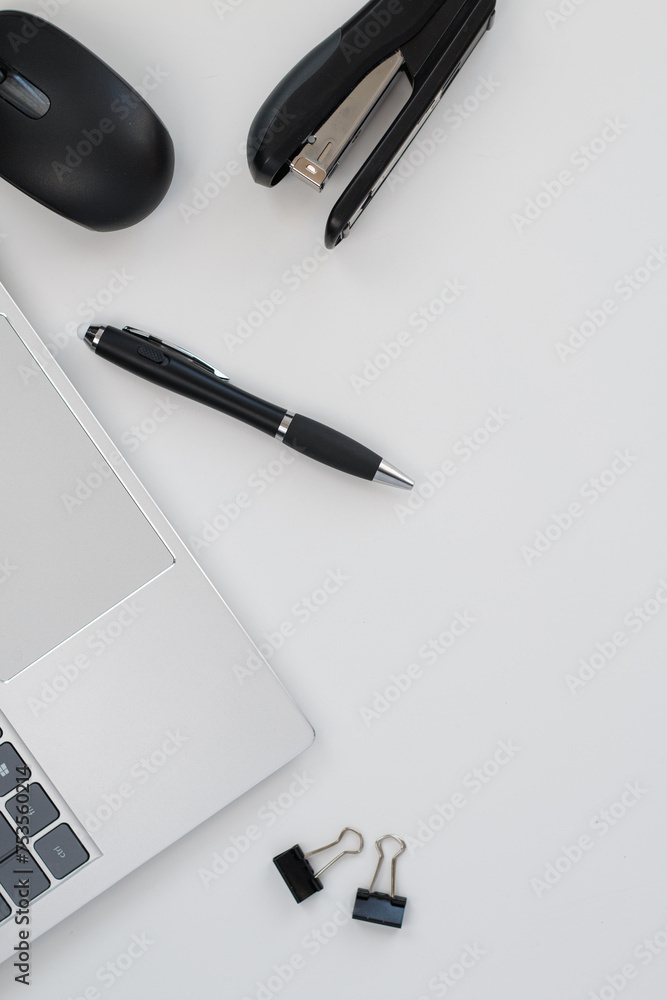 Top view of a silver laptop with black pen, mouse and stapler on an office desk. Top view of a silver laptop with black pen, mouse and stapler on an office desk.