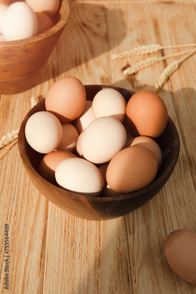 Chicken eggs of different brown and beige shades in a large wooden bowl on a wooden table with beige kitchen towel. Easter background. Top view Chicken eggs of different brown and beige shades in a large wooden bowl on a wooden table with beige kitchen towel. Easter background. Top view