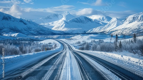 A snowy mountain road with a long stretch of road in between two mountains