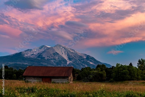 Barn structure in the center of a vast meadow under a sunset near Mt Sopris in Carbondale, Colorado photo