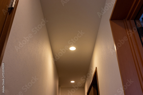 天井の小さなダウンライトで照らされた狭い廊下 