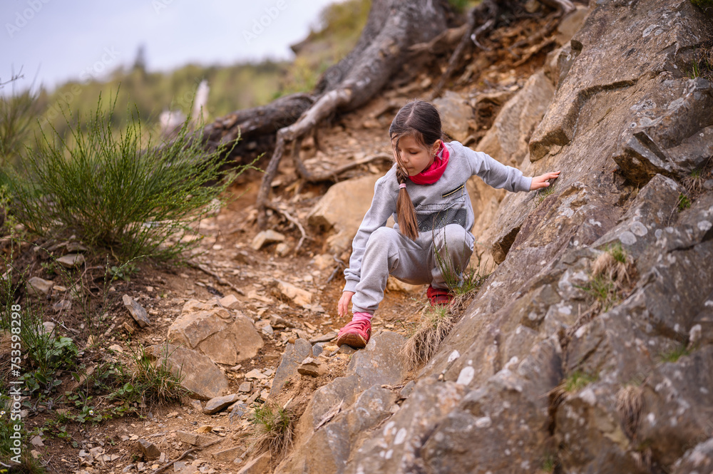 A focused young girl carefully navigates a rocky trail, displaying determination and the spirit of adventure in the great outdoors