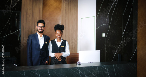 Portrait of polite, professional male and female workers of fancy hotel in uniform. Indian and African-American hotel managers smiling and looking into the camera. Customer care concept.