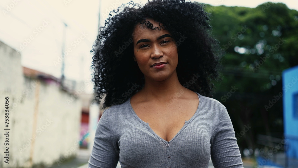 One confident young black Brazilian woman walking forward in city street with curly hair. 20s South American latina adult girl strolling in urban feeling secured and self-assured One confident young black Brazilian woman walking forward in city street with curly hair. 20s South American latina adult girl strolling in urban feeling secured and self-assured