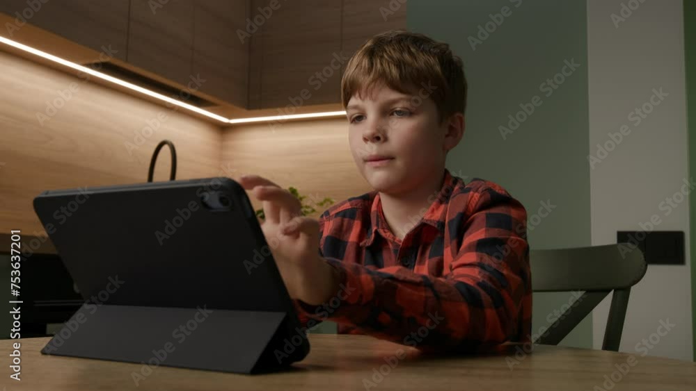 At home, a diligent schoolboy focuses on learning, using a tablet computer for educational activities and exploration At home, a diligent schoolboy focuses on learning, using a tablet computer for educational activities and exploration