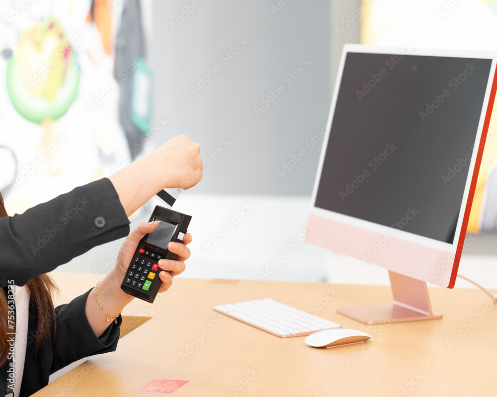Woman hands swiping card on terminal in front of flat monitor computer ...